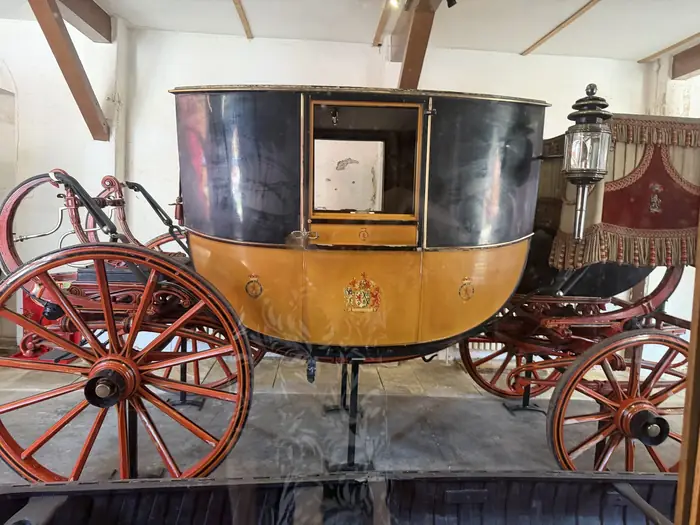 A state coach, the family arms on its door, in the old stables.